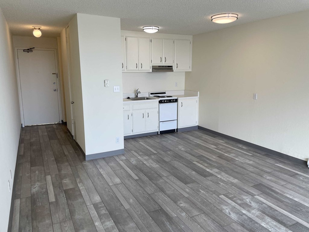an empty kitchen with white cabinets and a wood floor