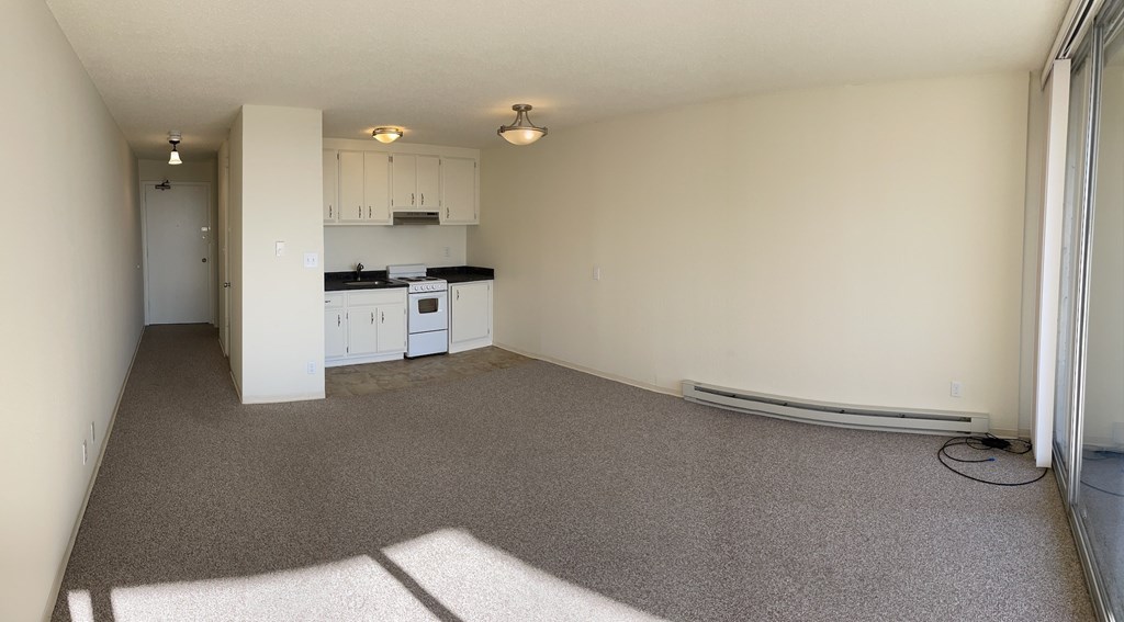 an empty kitchen and living room with a carpeted floor