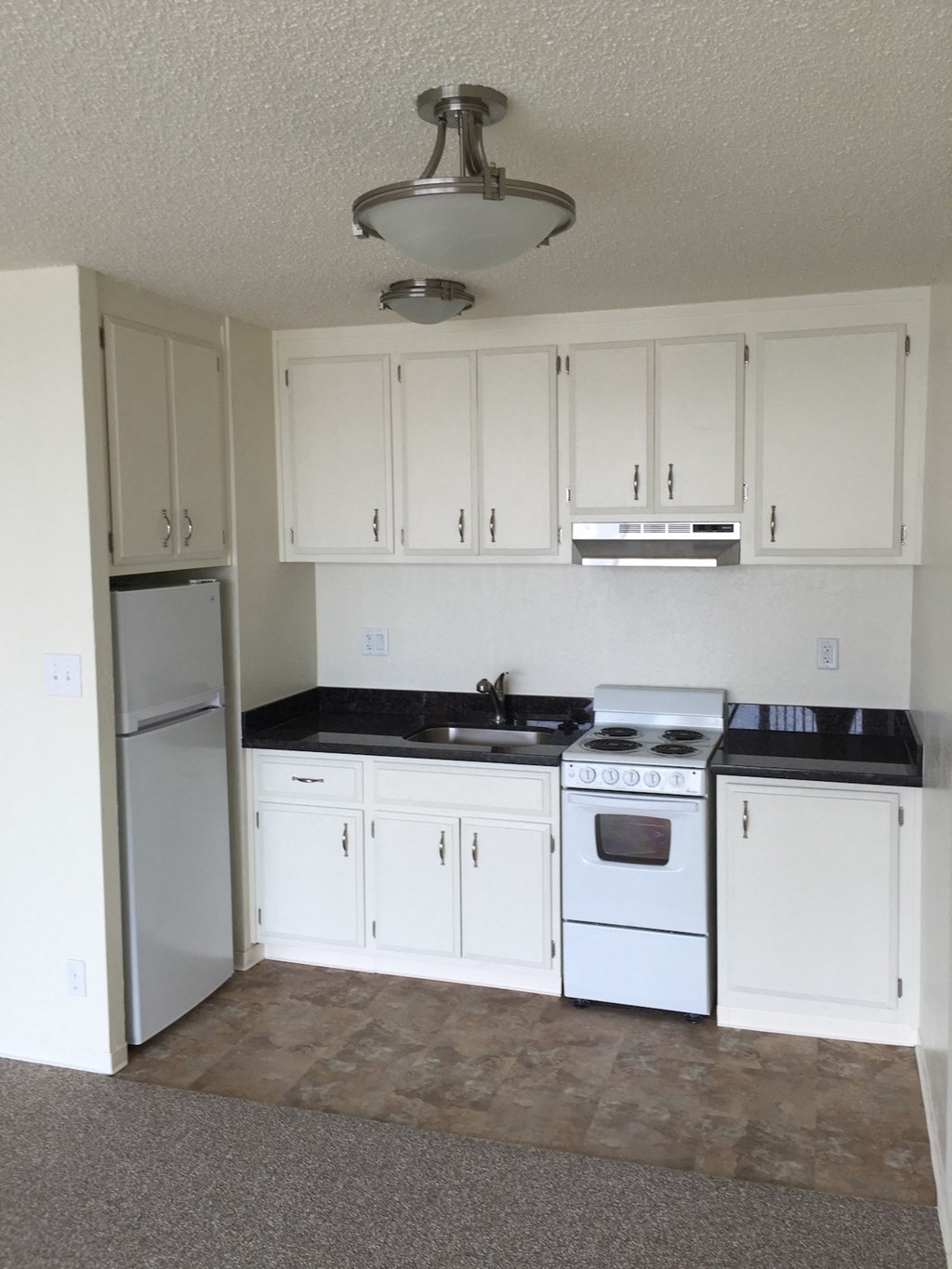 an empty kitchen with white cabinets and a stove and refrigerator