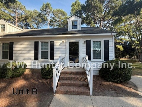 A white house with black shutters and a sign that says J.W. Hunter Company Inc.