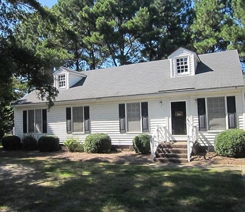 A white house with a grey roof and a black door.