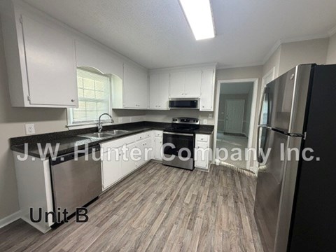 A kitchen with white cabinets and a black fridge is labeled Unit B.