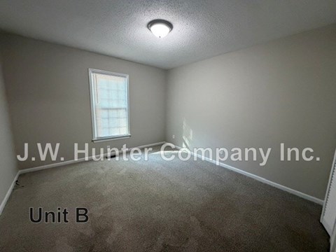 A room with carpet flooring and a window with blinds.