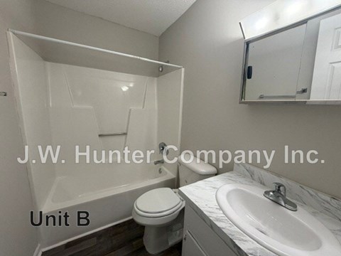 A bathroom with a toilet, sink, and mirror.