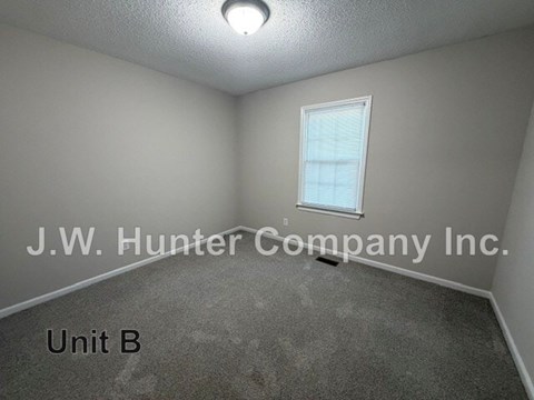 A room with a window and carpeted floor.