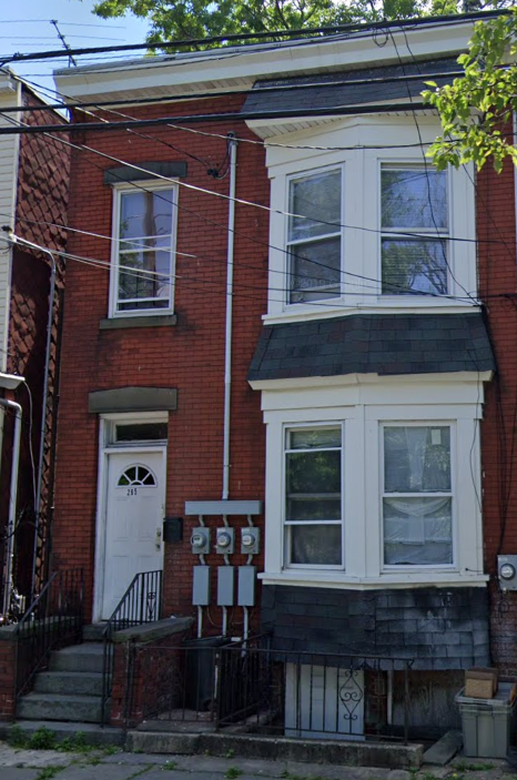 A red brick house with a white door and a window.