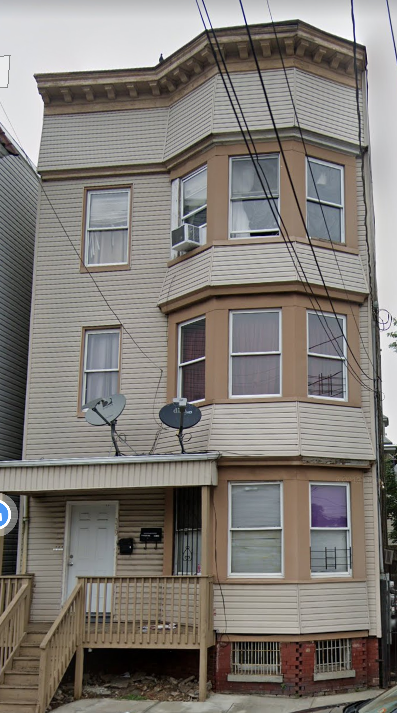 A three-story building with a balcony and satellite dishes on the roof.