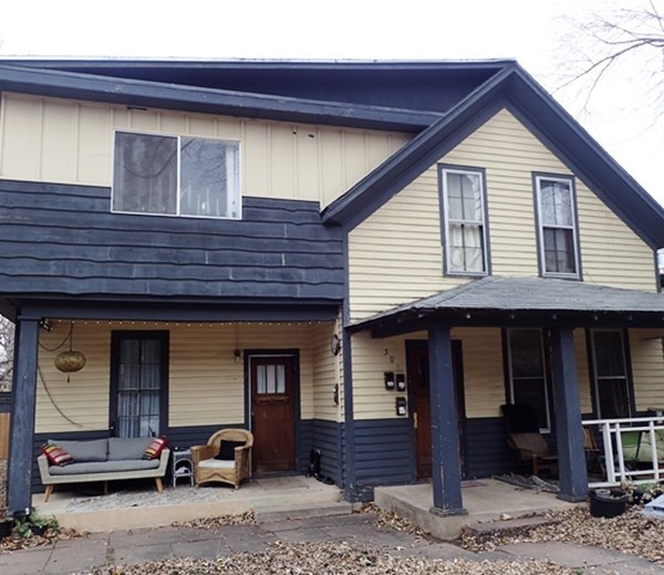 a yellow house with a blue roof and a porch