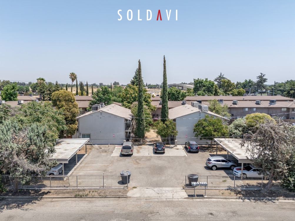 A parking lot with a building and trees in the background with the word soldavi on top.