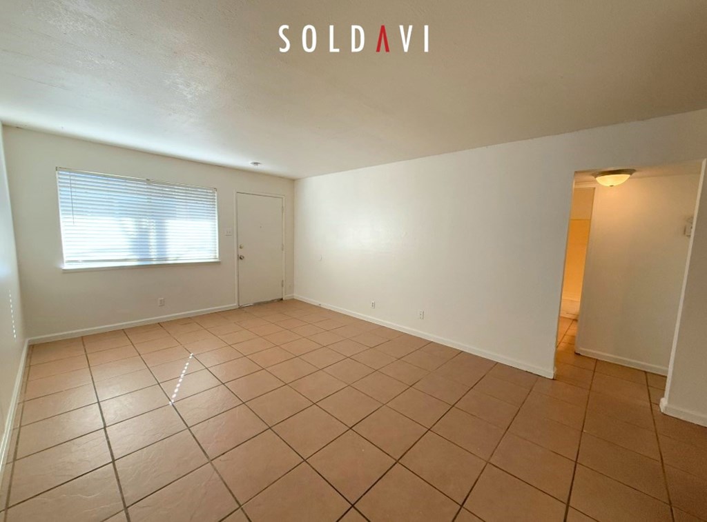 A room with tiled flooring and a window with blinds is for sale.