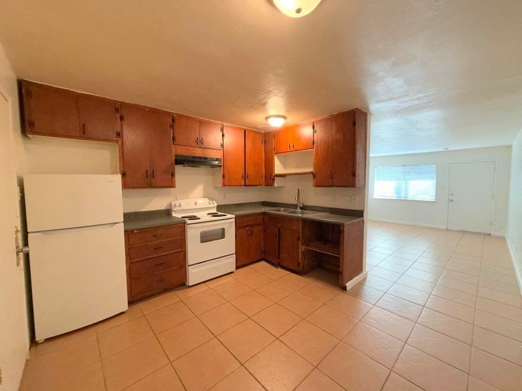 A kitchen with brown cabinets and white appliances.