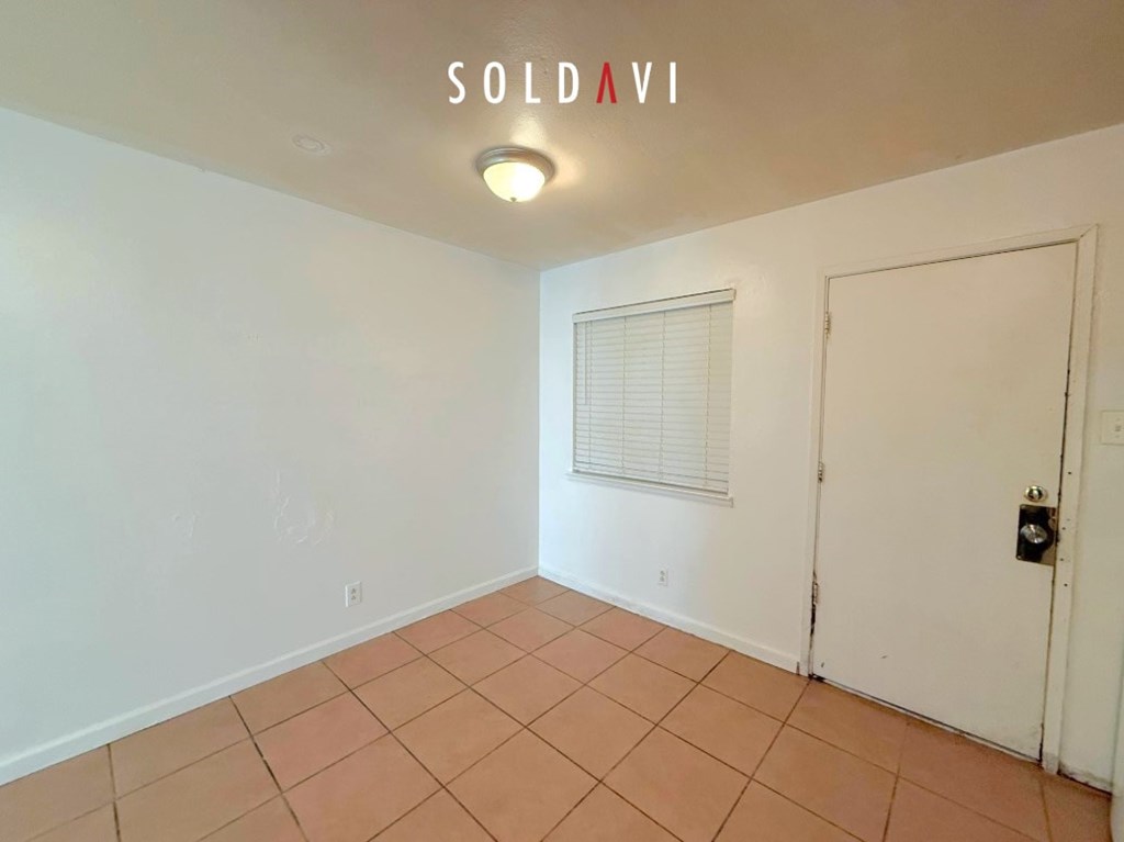 A room with a white door and a window with blinds.