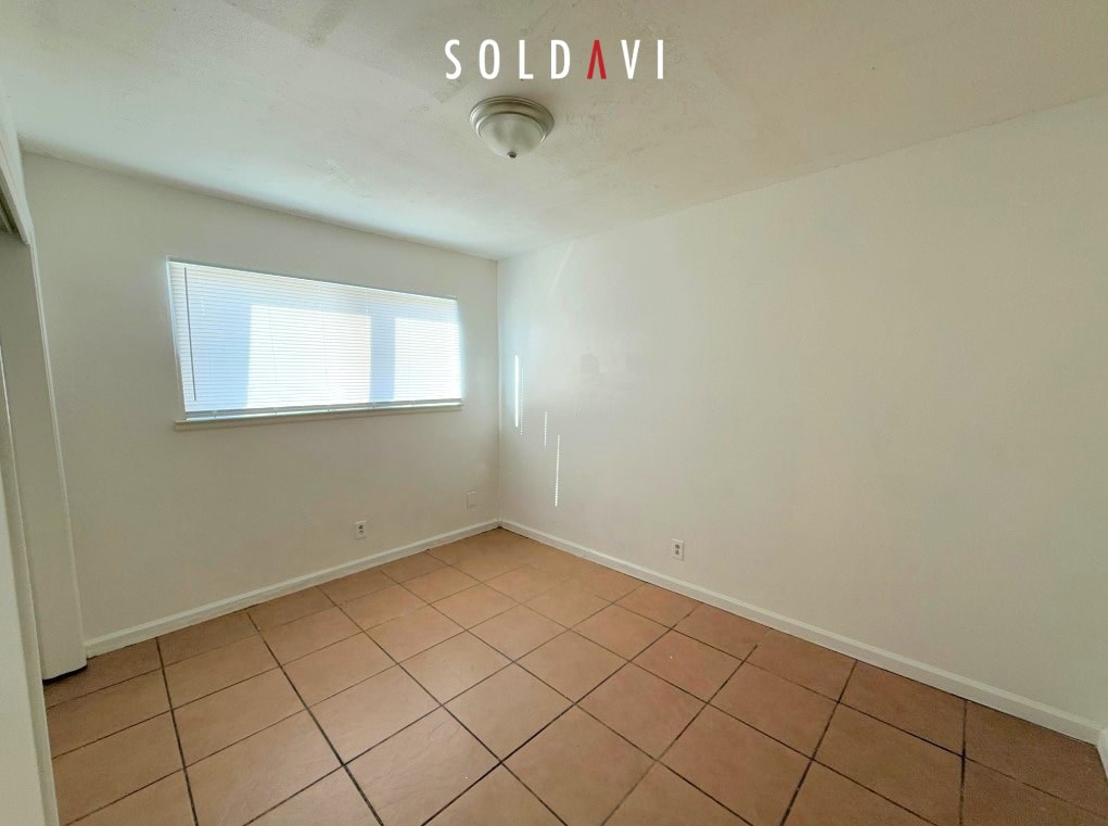 A room with a tiled floor and a window with blinds.