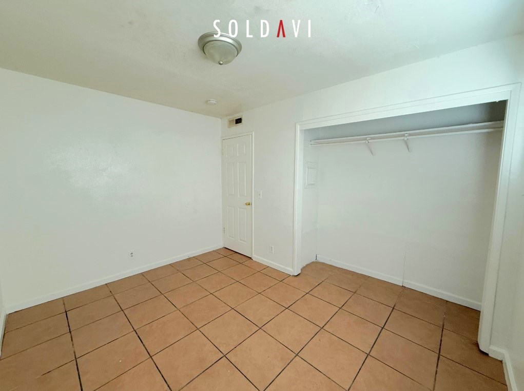 A room with a tiled floor and a closet with a white door.