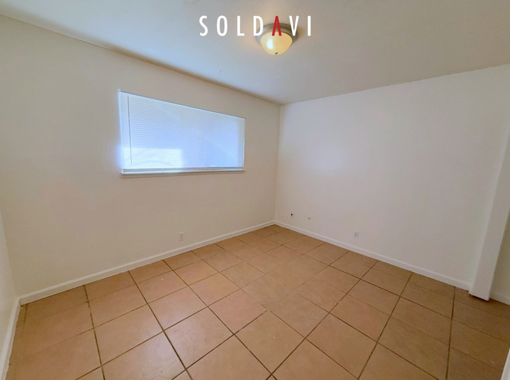 A room with a tiled floor and a window with blinds.