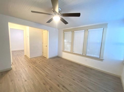 an empty living room with a ceiling fan and a window