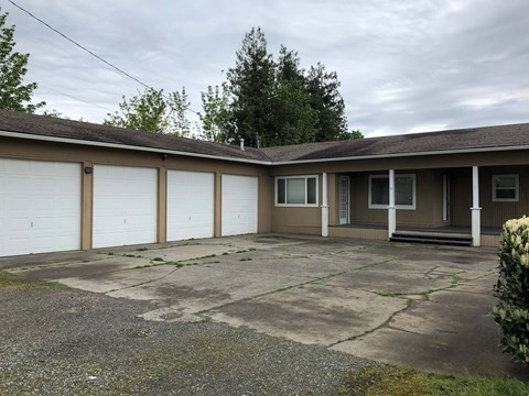 the front of a ranch house with white garage doors