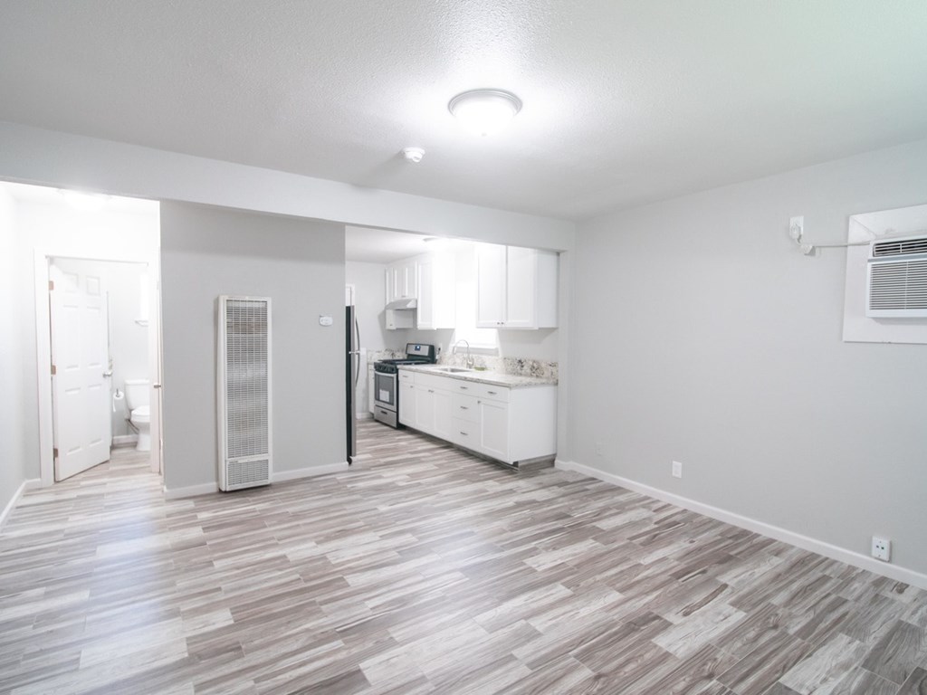 A kitchen with white cabinets and a refrigerator is visible from the living room.