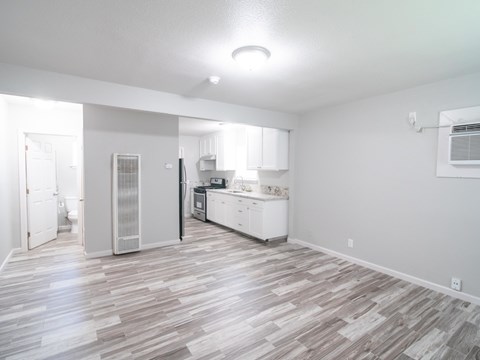 A kitchen with white cabinets and a refrigerator is visible from the living room.
