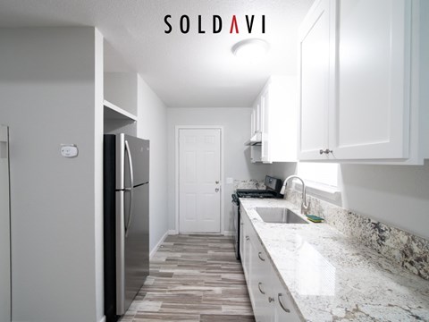 A kitchen with a refrigerator, sink, and cabinets is for sale.