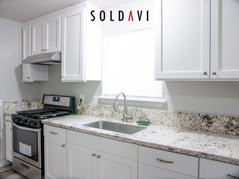 A kitchen with white cabinets and a granite countertop.