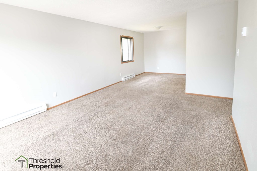 an empty living room with carpet and white walls