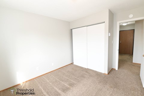 a bedroom with white walls and carpet and a closet