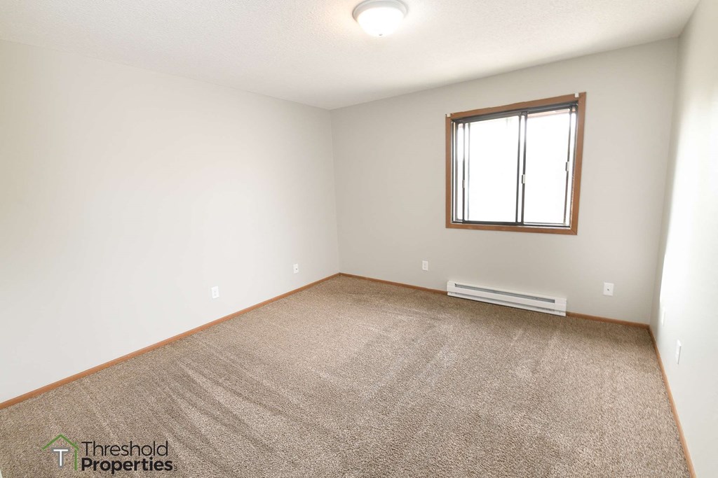 an empty living room with carpet and a window