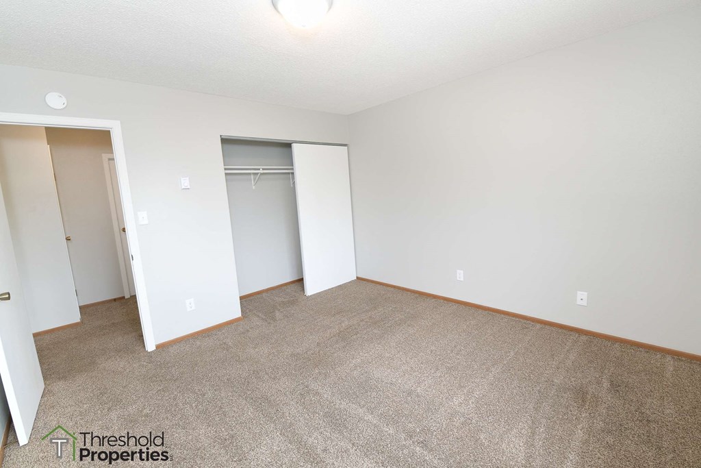 an empty living room with carpet and a closet
