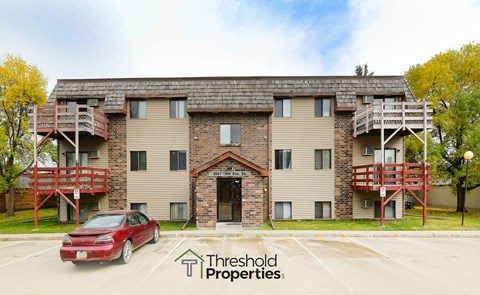 a view of an apartment building with a red car parked in front