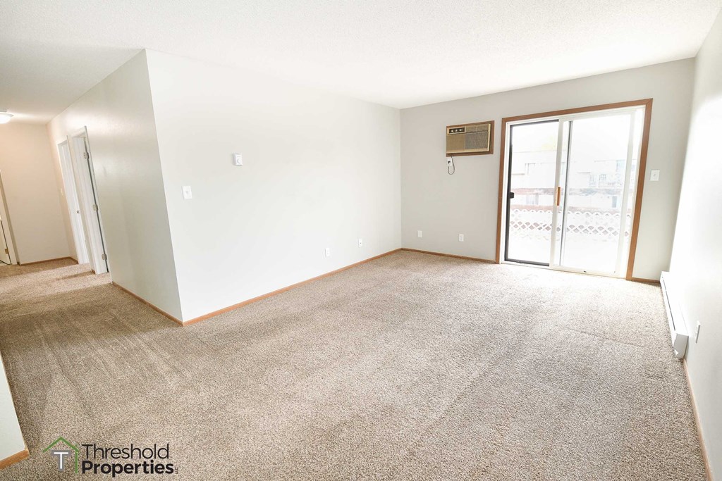 an empty living room with a door to a balcony
