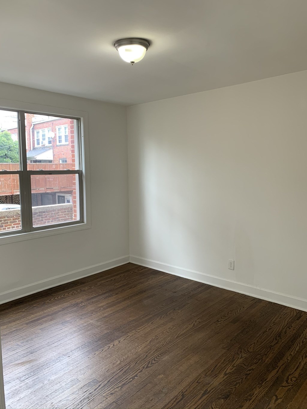 an empty living room with wood floors and a window