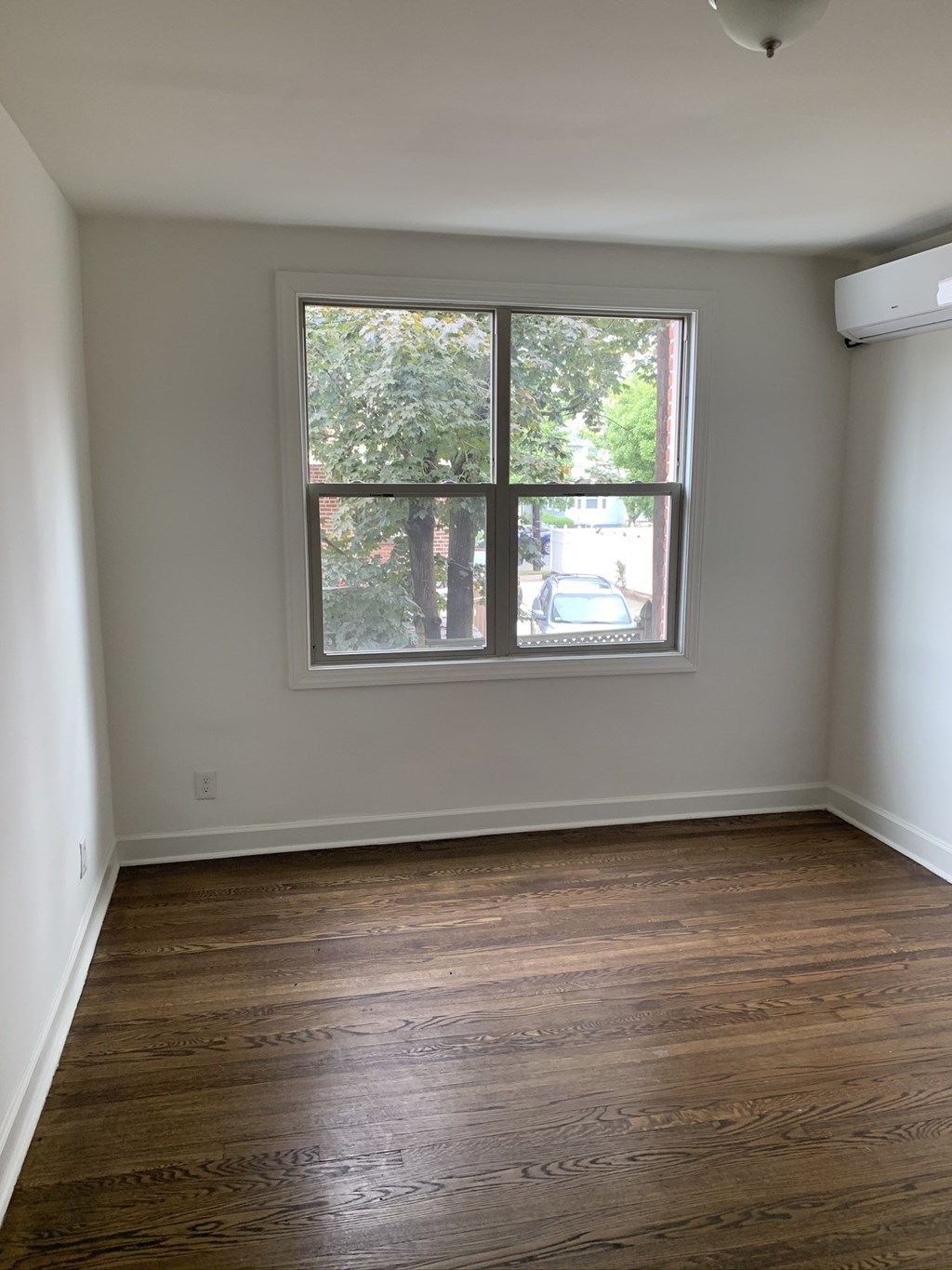 an empty room with a window and wooden floors