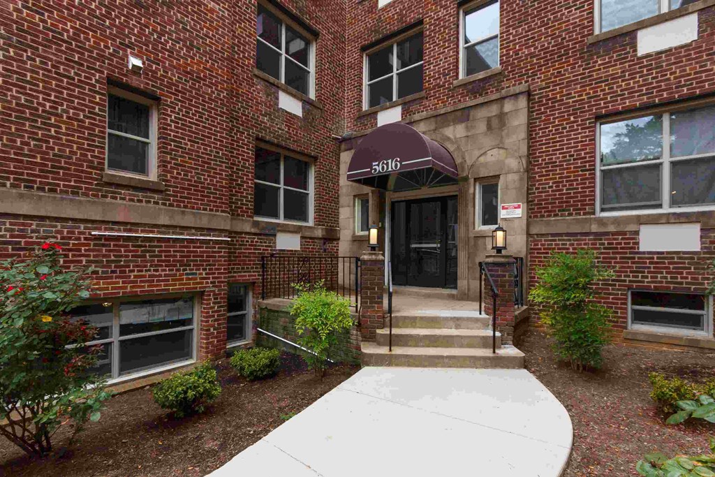 the front of a brick building with stairs and an umbrella
