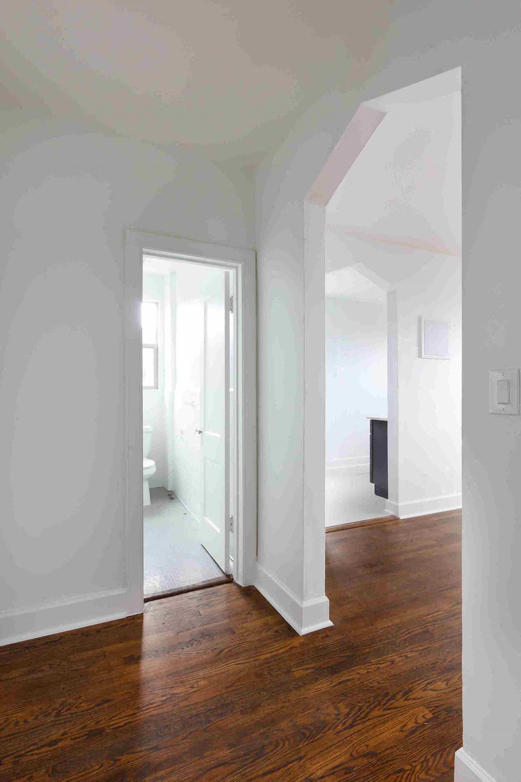 an empty room with white walls and wood floors