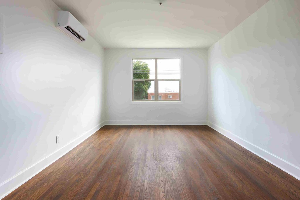 an empty room with wooden floors and a window
