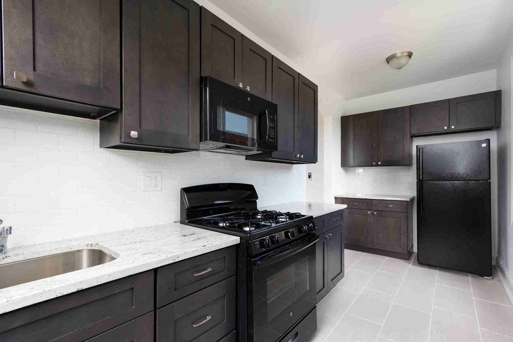 a kitchen with black cabinets and a stove and a microwave