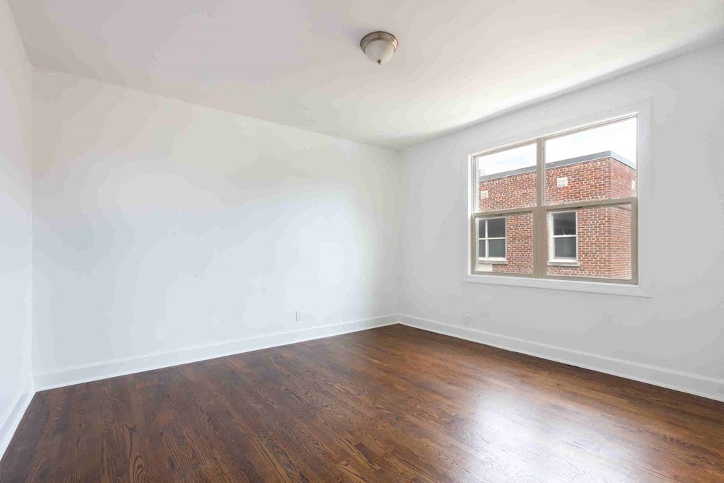 an empty room with wood floors and a window