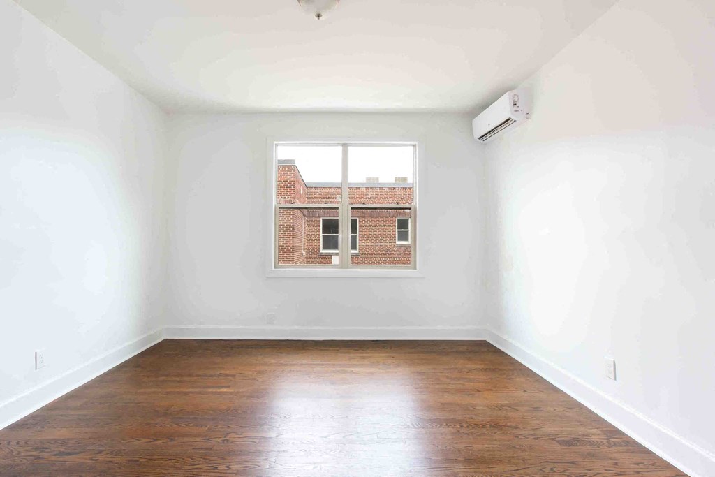 an empty room with a window and wooden floors