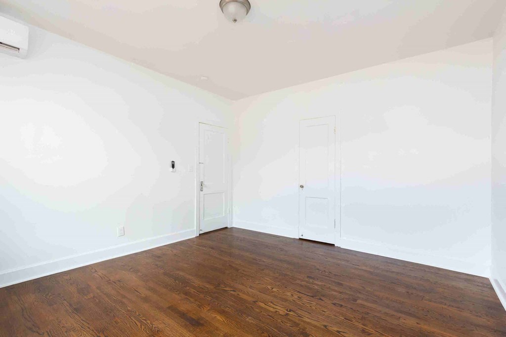 an empty room with white walls and wood floors