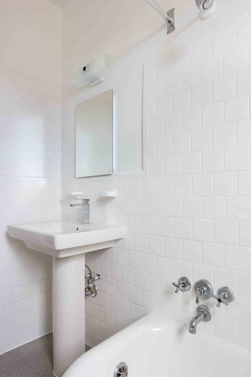 a white bathroom with a sink and tub and a mirror