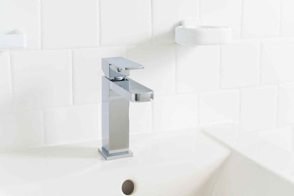 a white bathroom with a white sink and a silver faucet