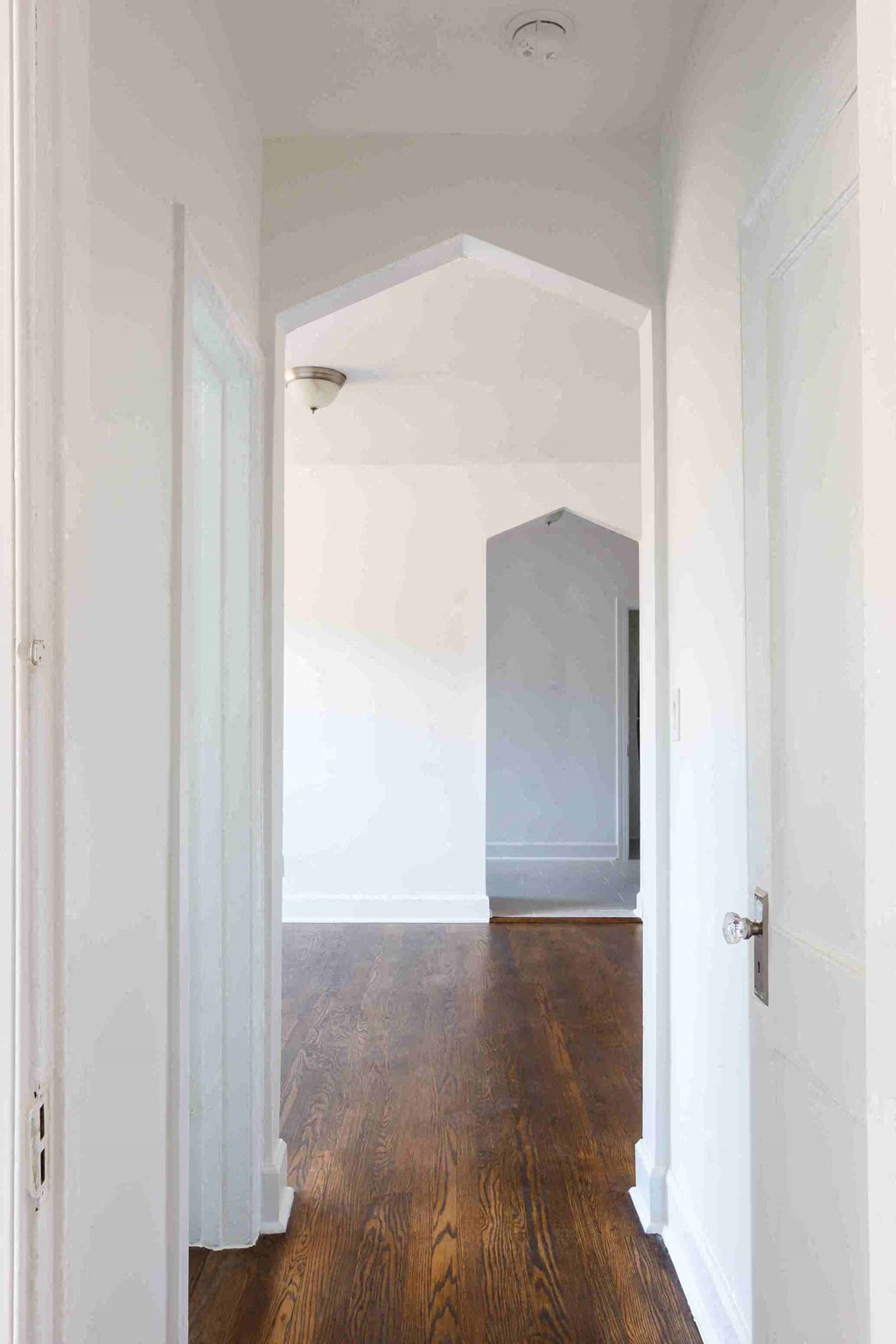an empty room with white walls and wood floors