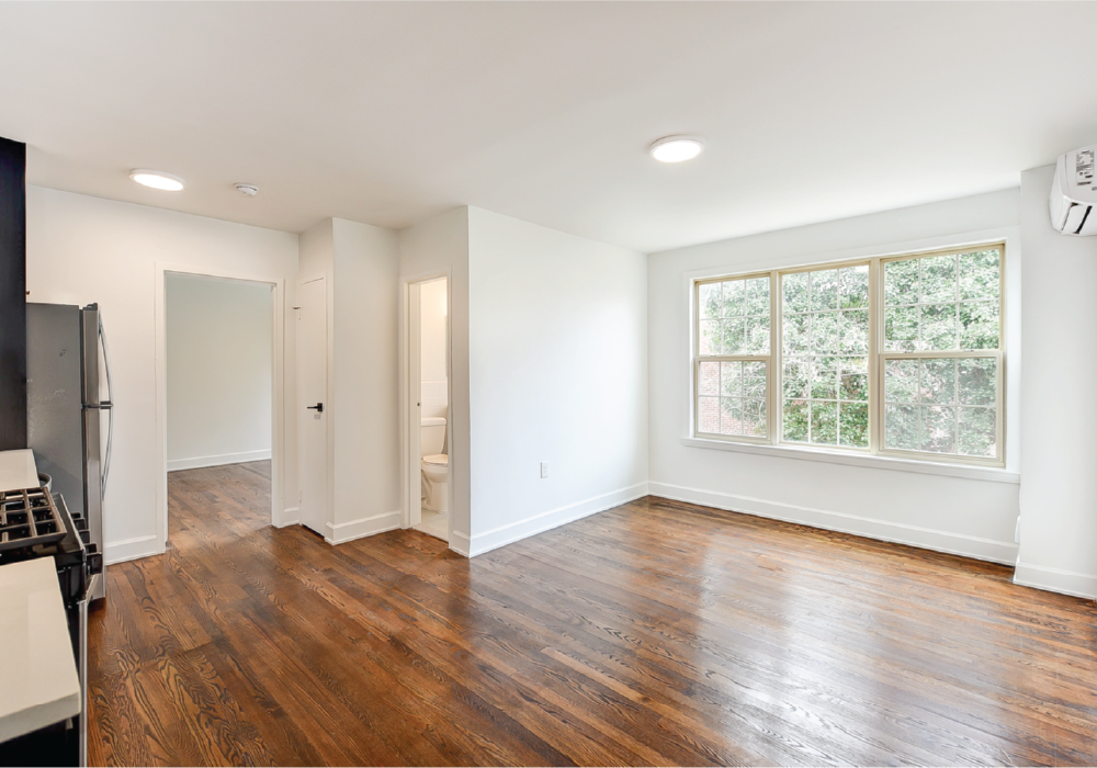 an empty living room with white walls and a large window