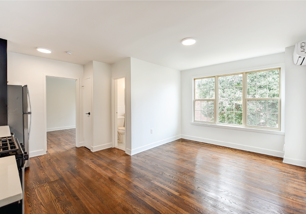 an empty living room with white walls and a large window