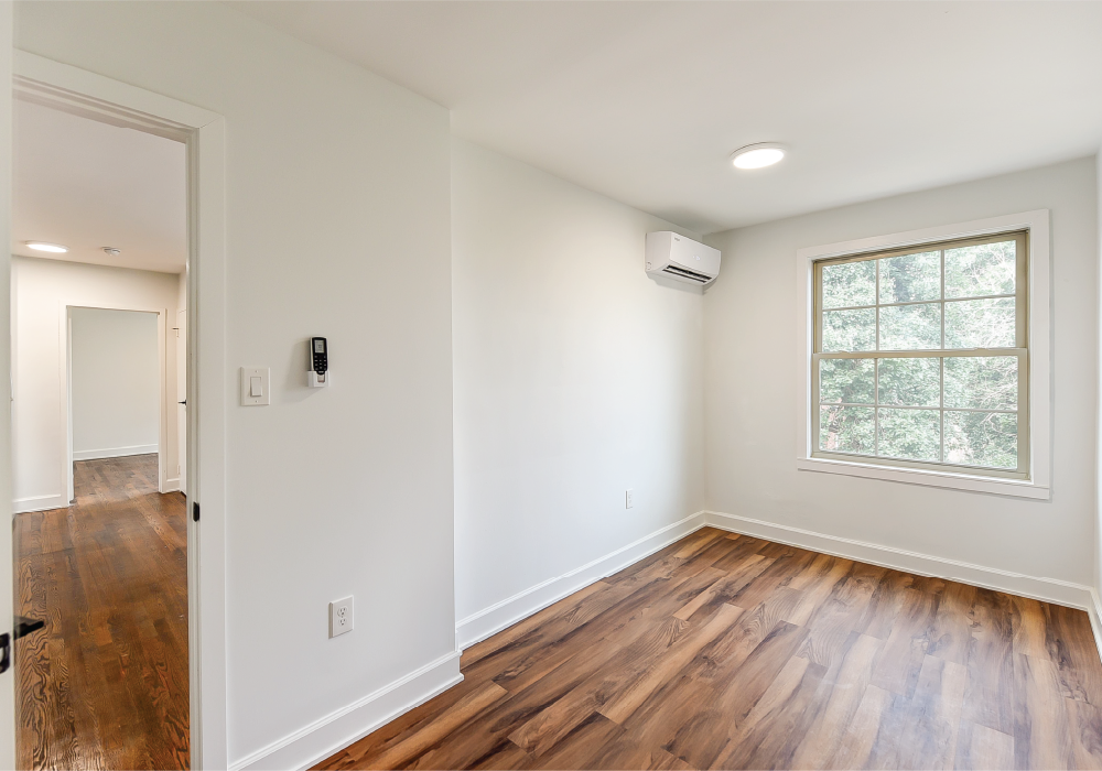 a living room with white walls and a window and wooden floors