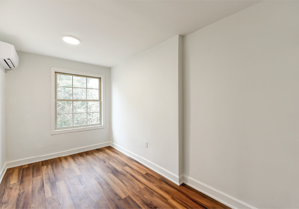 an empty room with white walls and wooden floors and a window