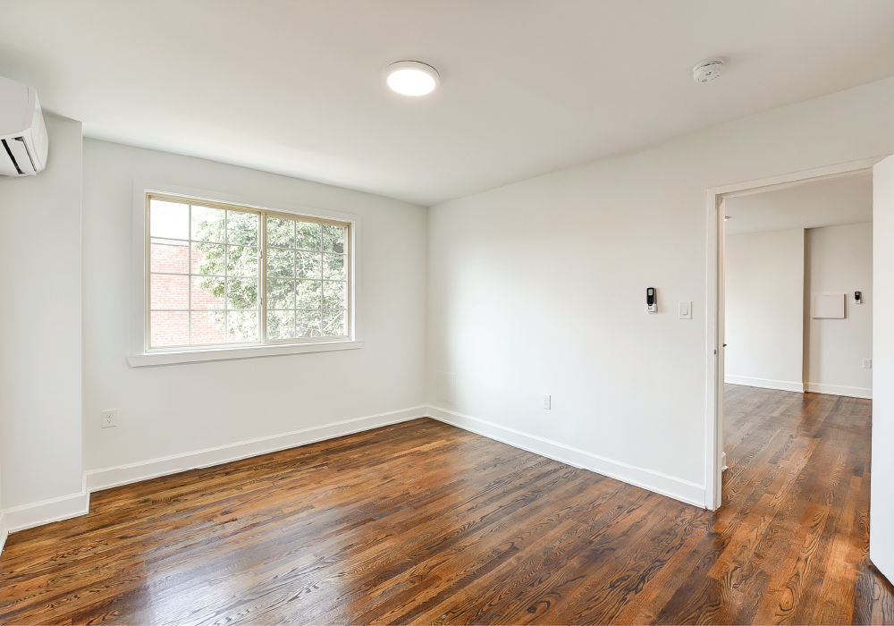 an empty living room with white walls and a window
