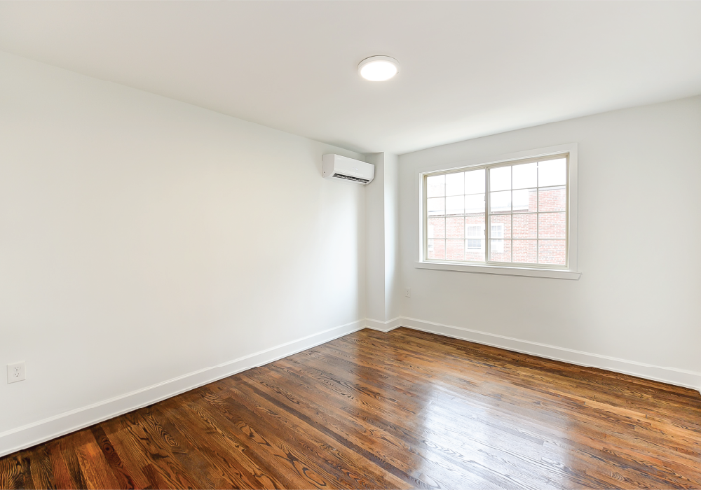an empty room with white walls and wood floors and a window