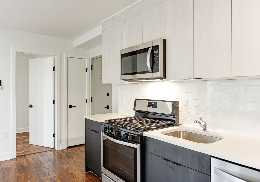 a kitchen with white cabinets and a stove and microwave and a sink